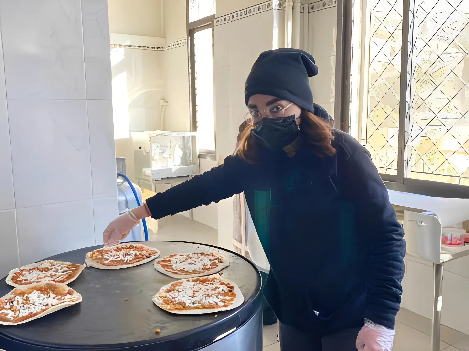 Woman preparing pizzas in kitchen