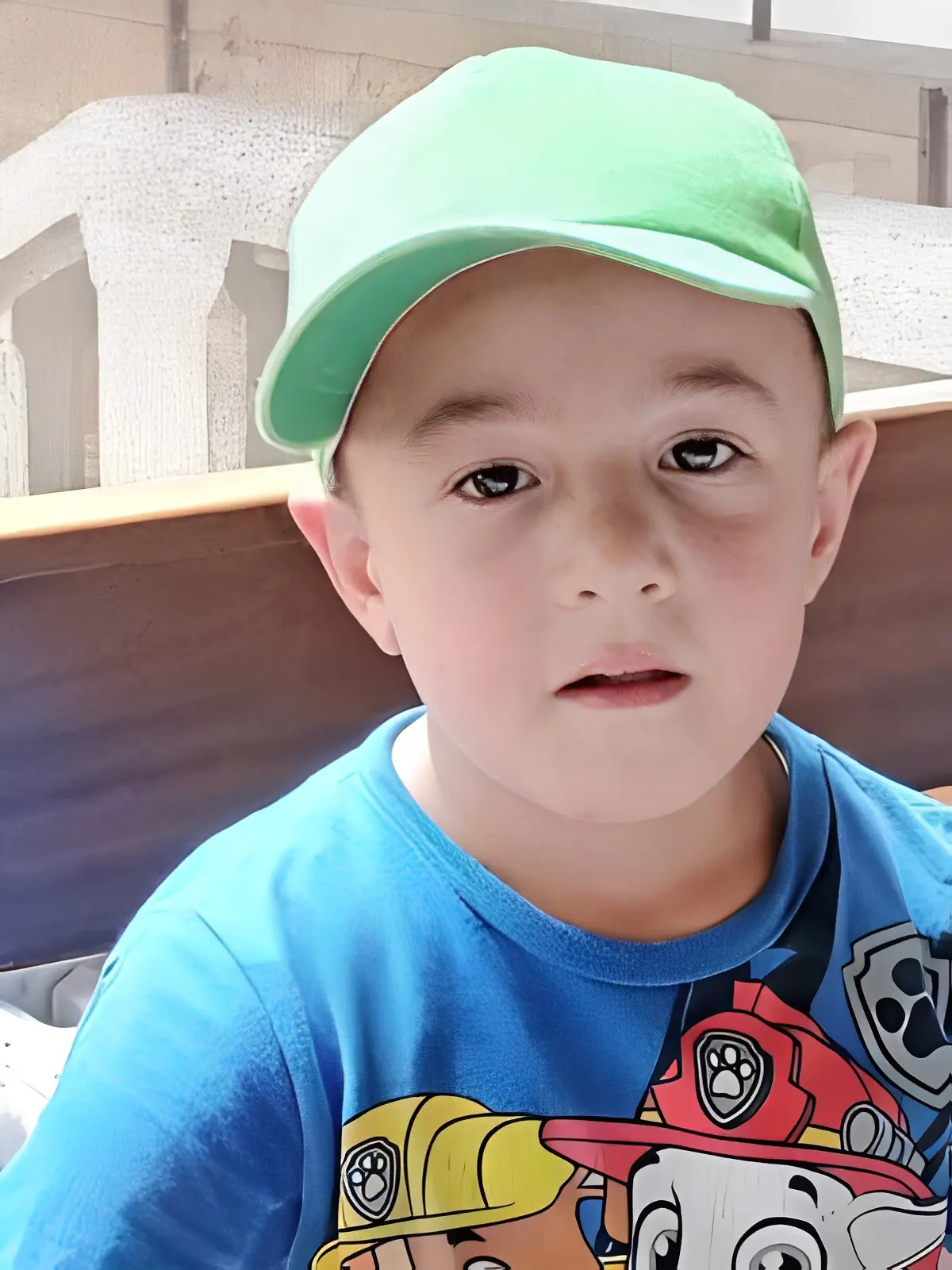 Child in green cap and blue shirt