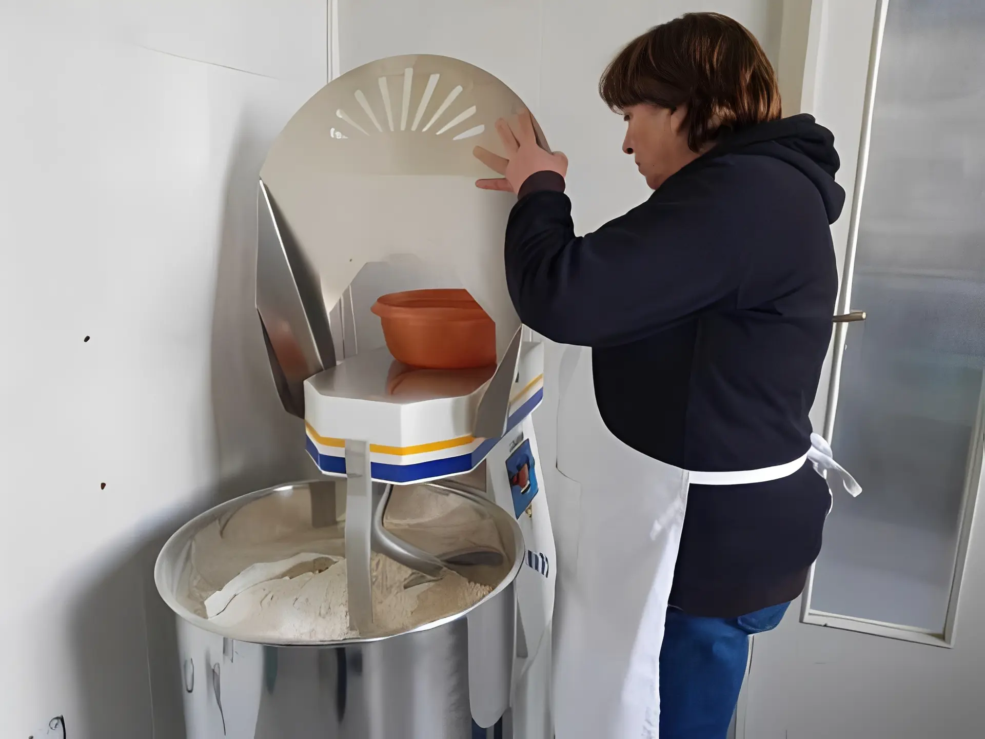 Bakery worker operating mixing machine