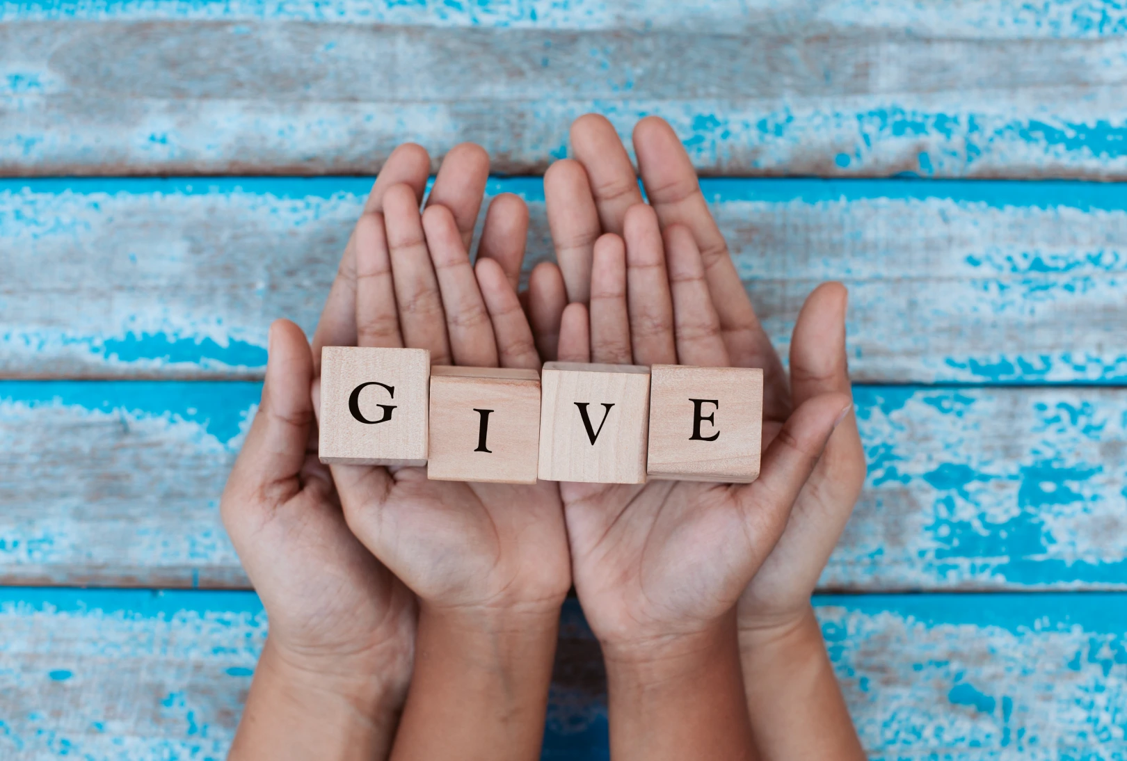 Giving concept with hands and letter blocks